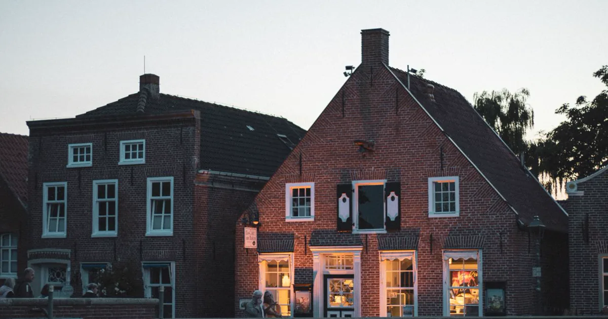 Woonhuis in de avond met verlichte ramen — 's avonds en 's nachts bepaalt het verbruik wat een thuisbatterij oplevert